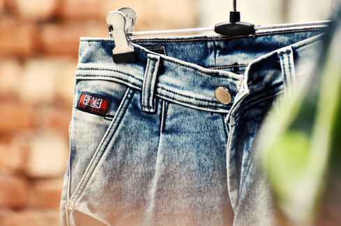 selective focus photography of blue denim bottoms hanged on gray metal hanger